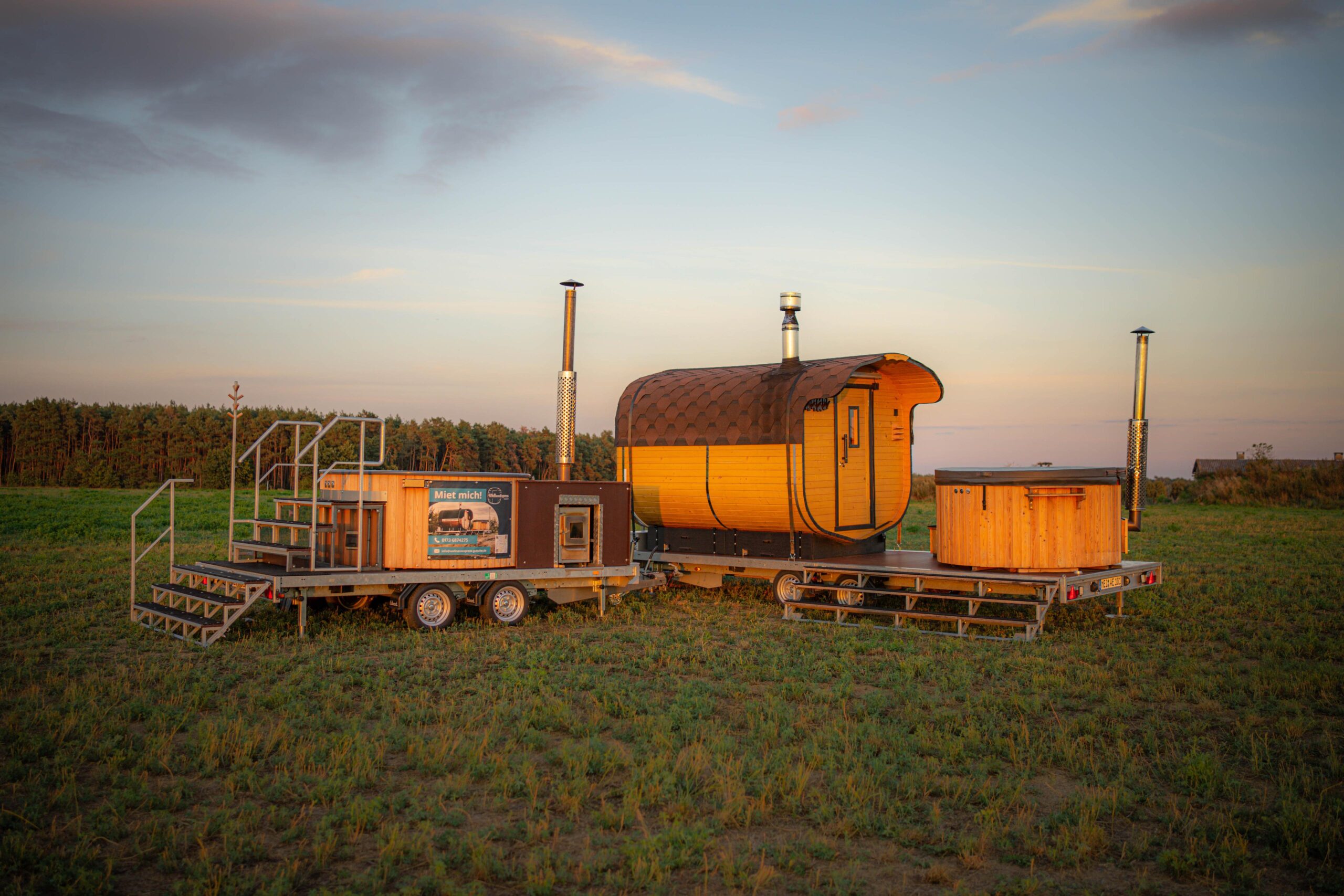 Sauna-Fass und Whirlpool-Anhänger von WellnessExpress-Gutsche auf der Wiese